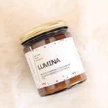 Load image into Gallery viewer, LUMINA Hand Poured Candle. White Pumpkin. Oat Milk. Barley. Cardamom. Saffron. Amber. Traditional Cotton Wick. 7 oz Amber Jar.