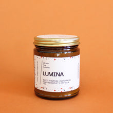 Load image into Gallery viewer, LUMINA Hand Poured Candle. White Pumpkin. Oat Milk. Barley. Cardamom. Saffron. Amber. Traditional Cotton Wick. 7 oz Amber Jar.